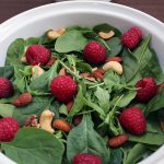 Salad of arugula, spinach, almonds, and raspberries with yogurt sauce