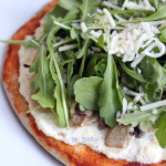 Pizza with ricotta, caramelized onions, mushrooms, and arugula